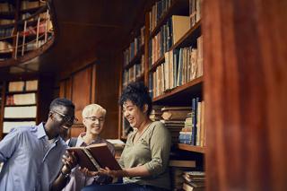 A group of people in a library sharing a book 